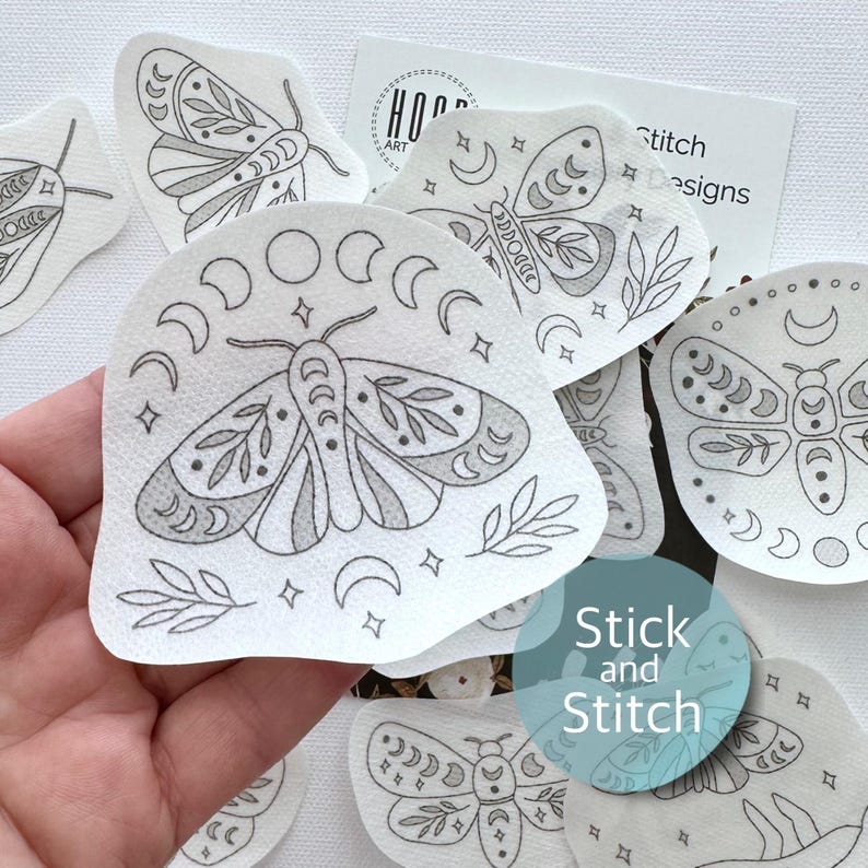 May include: A set of iron-on patches featuring black and white illustrations of moths with crescent moons and stars. The patches are labeled "Stick and Stitch".
