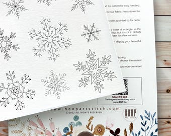 May include: A white paper sheet featuring black line art illustrations of various snowflake designs. The sheet includes printed instructional text, a QR code for a beginner embroidery stitch guide, and the Hoop Art Stitch logo at the bottom.
