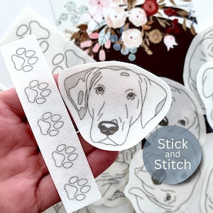 May include: A white felt dog head applique with black eyes and nose. The applique is part of a set of iron-on patches that say "Stick and Stitch".