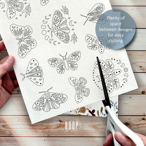 Puede incluir: Una hoja imprimible de 10 dibujos en blanco y negro de polillas con dise&ntilde;os florales y lunares. El texto "Plenty of space between designs for easy cutting" est&aacute; en un c&iacute;rculo azul en la esquina superior derecha de la hoja.