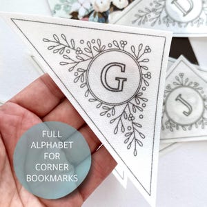 May include: A set of printable corner bookmarks featuring a floral design with a letter in a circle. The letter G is shown in the image. The text "FULL ALPHABET FOR CORNER BOOKMARKS" is printed below the image.