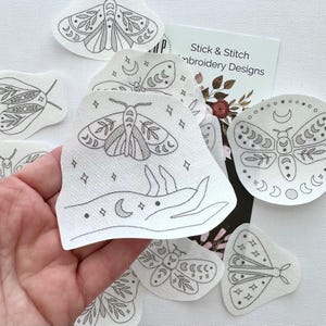May include: A set of 10 iron-on embroidery designs featuring moths, moons, and stars. The designs are printed on white fabric and are perfect for adding a touch of whimsy to your projects.