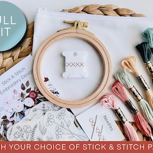 May include: An embroidery kit with a wooden hoop, needles, and colorful thread spools. The kit includes a white zippered pouch, a design booklet, and a "FULL KIT" label. The text "Stick & Stitch Embroidery Design" is visible.
