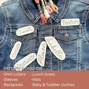 May include: A close-up of a denim jacket with several white fabric labels sewn on. The labels have names written on them, including "Charlotte", "Teodore", "Isabella", and "Alison". The text "PATTERN WORKS ON:" is written below the labels, followed by a list of uses for the labels, such as "Shirt collars", "Lunch boxes", "Sleeves", "Hats", "Backpacks", and "Baby & Toddler clothes".