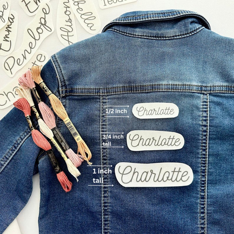 May include: Three iron-on name labels in different sizes, 1/2 inch, 3/4 inch tall, and 1 inch tall, with the name Charlotte printed on each. The labels are on a blue denim jacket.