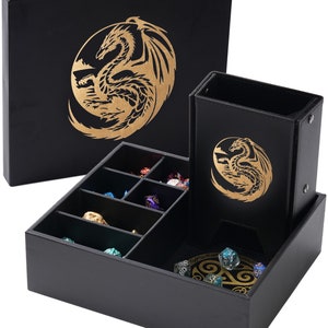 May include: Black leather dice box with a gold dragon design. The box has a removable tray with compartments for dice and a separate compartment for cards. The box is closed and the lid is on top.