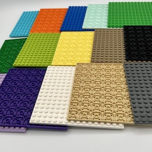 May include: A collection of colorful building block baseplates in various colors, including blue, orange, green, yellow, and purple. The plates have a textured surface with circular studs for attaching building blocks. The image showcases a variety of sizes and designs.