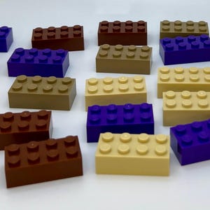 May include: An assortment of colorful toy building blocks in various shades of brown, tan, and purple. The blocks are rectangular with raised studs on top, designed for connecting to other blocks. The blocks are arranged on a white surface.