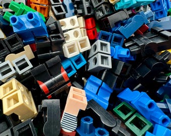 May include: A close-up shot of a pile of colorful plastic building blocks. The blocks are in various shapes and sizes, with colors including blue, black, white, red, and green. Some blocks have holes or pegs.