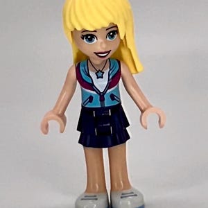 Stephanie wearing a dark blue layered skirt and medium azure and dark purple jacket LEGO® Friends Minifigure.