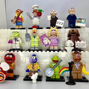 May include: A collection of 12 Muppet character LEGO minifigures, including Miss Piggy, Kermit the Frog, Animal, and Fozzie Bear. The minifigures are all in different poses and have various accessories, such as musical instruments, a microphone, and a drum set.