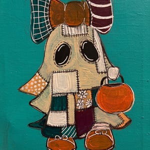 Pu&ograve; includere: Un dipinto su sfondo verde acqua raffigurante un personaggio fantasma che indossa un lenzuolo patchwork con vari motivi e colori. Il fantasma ha un grande fiocco sulla testa, occhi ovali neri e tiene in mano un secchiello a forma di zucca.