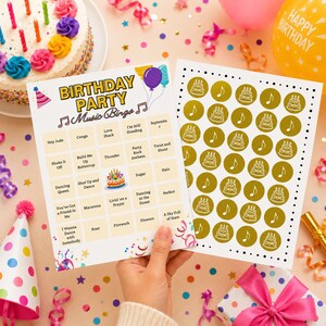 May include: A birthday party music bingo game card featuring a grid of song titles and a matching sheet of gold circular markers with cake and music note icons. The bingo card includes the text Birthday Party Music Bingo and song titles.