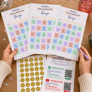 May include: Three 2000s Throwback Bingo game sheets with colorful squares and the game title in a script font. A sheet of gold music note stickers and a bonus playlist link sheet are also visible. A disco ball and popcorn bowl are in the background.