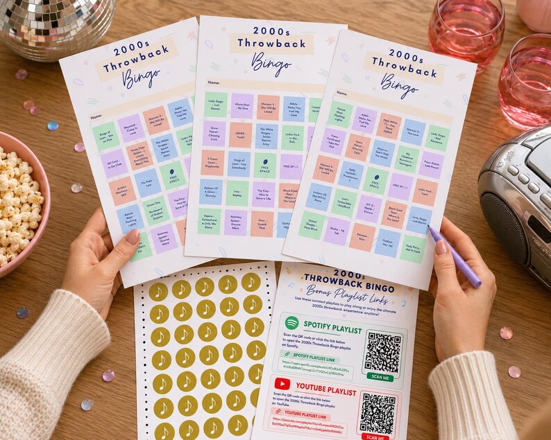 May include: Three 2000s Throwback Bingo game sheets with colorful squares and the game title in a script font. A sheet of gold music note stickers and a bonus playlist link sheet are also visible. A disco ball and popcorn bowl are in the background.