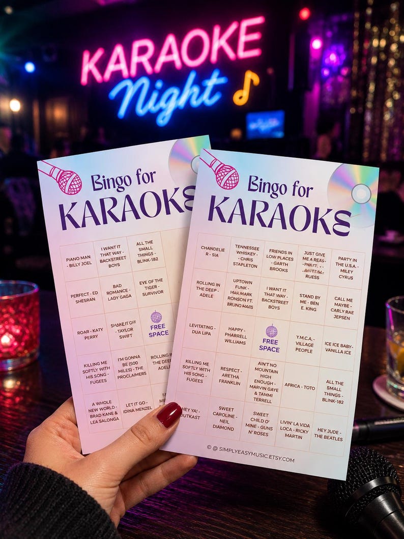 May include: Two Bingo cards for Karaoke Night, featuring song titles like "Piano Man" and "Sweet Caroline." The cards are held in a person's hand, with a neon "Karaoke Night" sign in the background.