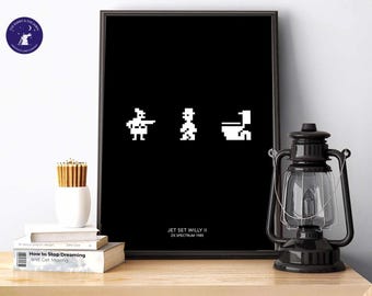 May include: Black framed print featuring pixelated figures from the video game Jet Set Willy II. The artwork displays three white figures on a black background. The text "JET SET WILLY II ZX SPECTRUM 1985" is printed at the bottom.