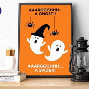 Puede incluir: Un estampado enmarcado con tem&aacute;tica de Halloween con fondo naranja. El estampado presenta dos fantasmas blancos de dibujos animados, ara&ntilde;as negras y las frases "AAARGGGHHH... A GHOST!!" y "AAARGGGHHH... A SPIDER!" en texto negro.