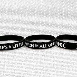 Könnte beinhalten: Drei schwarze Silikonarmbänder mit weißem Text. Das erste Armband sagt "There's a little witch in all of us". Das zweite Armband hat ein Halbmond- und ein Vollmonddesign. Das dritte Armband hat ein Halbmond- und ein Vollmonddesign.