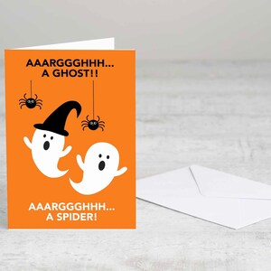 Puede incluir: Tarjeta de felicitaci&oacute;n de Halloween con fondo naranja. La tarjeta presenta dos fantasmas de dibujos animados blancos, uno con un sombrero de bruja negro y dos ara&ntilde;as negras. El texto dice "AAARGGGHHH... A GHOST!!" y "AAARGGGHHH... A SPIDER!". Se incluye un sobre blanco.
