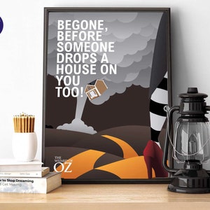 May include: Framed art print with text from The Wizard of Oz: "BEGONE, BEFORE SOMEONE DROPS A HOUSE ON YOU TOO!". The image shows a house falling from a tornado, a yellow brick road, and the Wicked Witch's legs.