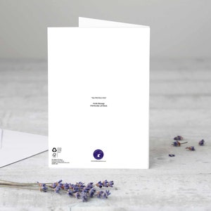 Puede incluir: Una tarjeta de felicitaci&oacute;n blanca con el texto "The Wild Moon Child" y "Inside Message Intentionally Left Blank". Tambi&eacute;n hay un sobre blanco y ramitas de lavanda. La tarjeta tiene un logotipo en la esquina inferior derecha.