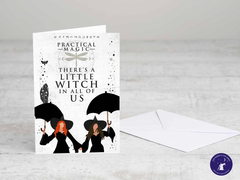 May include: A white card with a black and white illustration of two witches under umbrellas. The text on the card reads "Practical Magic" and "There's a little witch in all of us."