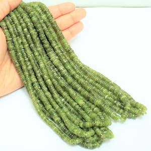以下が含まれることがあります： 緑色の宝石ビーズのストランド。各ビーズは、わずかに不規則な形状の小さな平らな円盤です。ビーズは透明な糸に通されており、直径は約4mmです。