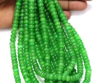 May include: A collection of bright green beads, each with a rounded form. The beads are strung together, forming multiple strands. The beads are a vibrant, solid green colour, and the background is white.