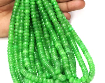 May include: A strand of bright green beads. The beads are small, round, and evenly sized, creating a consistent texture. The beads are a vibrant, light green colour, and appear to be made of a smooth, possibly polished material. The beads are held in a hand.