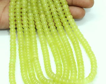 May include: A strand of light green jade beads. The beads are round and smooth, and they are strung on a white thread.