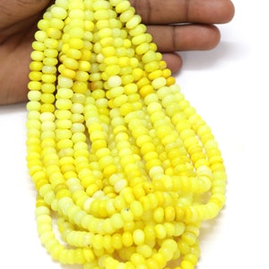 May include: A strand of bright yellow gemstone beads. The beads are round and smooth, and they are strung on a clear thread. The beads are approximately 6mm in diameter.