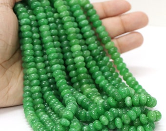 May include: A strand of bright green jade beads. The beads are round and smooth, and they are strung on a clear thread. The beads are all approximately the same size.