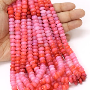 Może przedstawiać: Szereg różowych i czerwonych koralików z kamieni szlachetnych. Koraliki są okrągłe i mają gładkie, polerowane wykończenie.