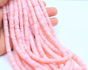 Pode incluir: Um fio de contas de opala rosa, cada conta é um pequeno disco plano com uma borda ligeiramente arredondada. As contas são enfiadas em um fio transparente.