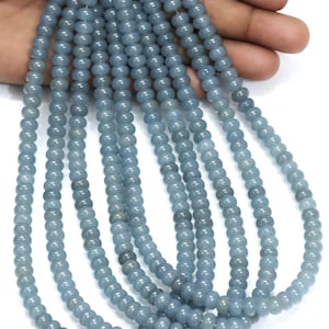 Könnte beinhalten: Eine Strähne aus hellblauen Edelsteinperlen. Die Perlen sind rund und glatt und auf einem durchsichtigen Faden aufgefädelt. Die Perlen haben einen Durchmesser von etwa 6 mm.