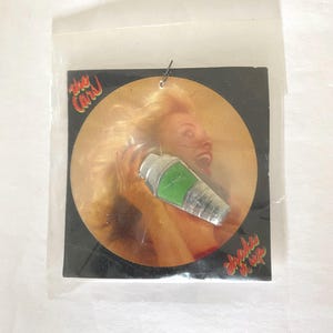 May include: A silver and green cocktail shaker with the text "The Cars" and "Shake It Up" on a black and orange background.