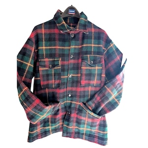 May include: A long-sleeved button-up shirt featuring a plaid pattern in dark green, black, and red with thin yellow lines. The shirt includes a standard collar, a front button placket, and two chest pockets with buttoned flaps on the front.