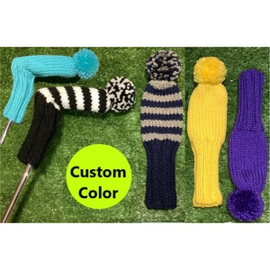 May include: Five knitted golf club head covers in various colors and patterns. The covers are striped, solid, and have pom-poms. The text "Custom Color" is visible in the image.