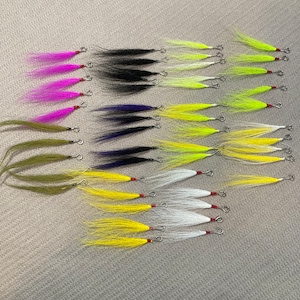 May include: Assortment of fly fishing lures with different colored feathers and materials. The lures are tied on hooks with red beads and silver swivels.