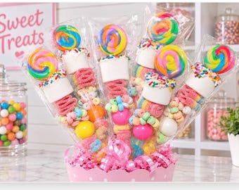 May include: A bouquet of five individually wrapped candy skewers arranged in a pink scalloped container. Each skewer features a colorful swirled lollipop, a large white marshmallow topped with rainbow sprinkles, and various gummy candies.