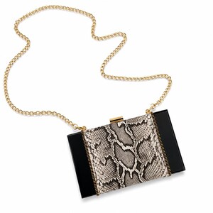 May include: A rectangular box clutch featuring a central panel with a grey and black snakeskin pattern, flanked by solid black side panels. The bag includes a gold-tone metal clasp closure and a matching gold-tone chain shoulder strap.