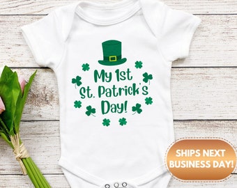 May include: White baby onesie with a green shamrock hat and the text "My 1st St. Patrick's Day!" surrounded by shamrocks.