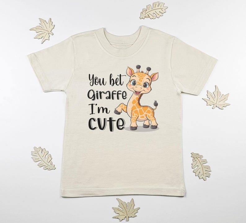 May include: A cream colored t-shirt with a cartoon giraffe and the text "You bet Giraffe I'm cute".