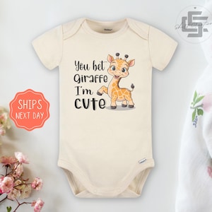 May include: A cream colored baby onesie with a cartoon giraffe and the text "You bet Giraffe I'm cute".