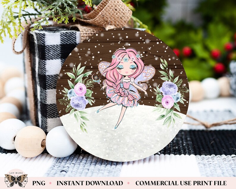 May include: A round wooden ornament with a winter scene featuring a fairy with pink hair and a pink dress. The fairy is surrounded by snowflakes and flowers. The ornament is perfect for adding a touch of whimsy to your holiday decor.