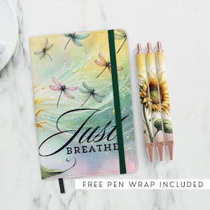 May include: A green and white journal with a dragonfly and sunflower design. The cover reads "Just Breathe". The journal comes with three matching pens.
