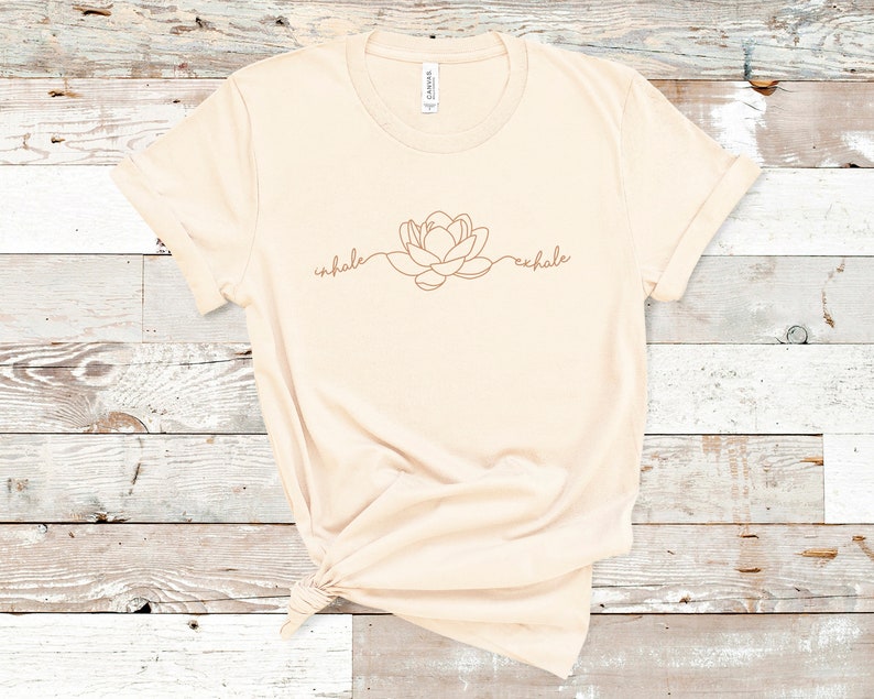 May include: A beige t-shirt with a brown line drawing of a flower and the words "inhale" and "exhale" on the front.