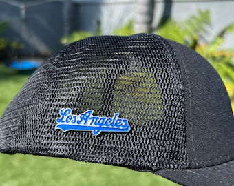 May include: Black mesh baseball cap with a blue and white "Los Angeles" embroidered on the front.