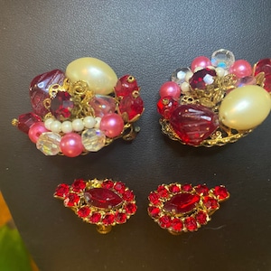 Pode incluir: Um par de brincos vintage de clip com contas vermelhas, cor-de-rosa e brancas e pérolas falsas. Os brincos têm uma base de metal dourado.
